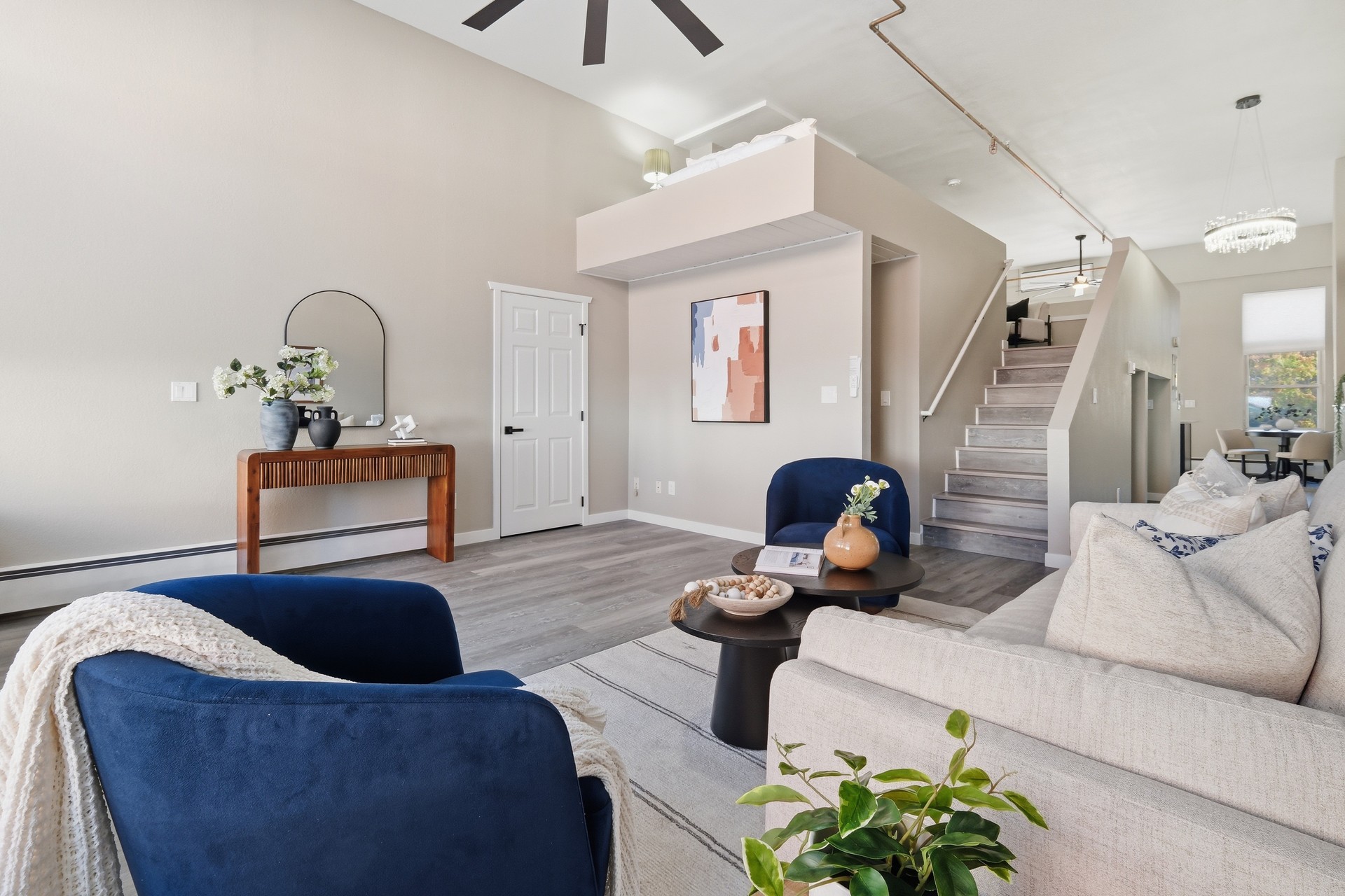 Zuni Loft living room with navy chairs, cream sofa, console table and stairs to the open loft bedroom
