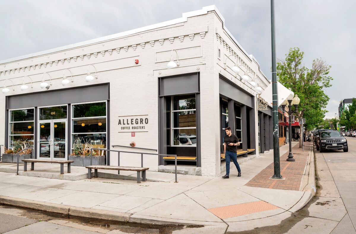 White brick corner coffee roaster storefront with sidewalk benches in Denver's LoHi neighborhood