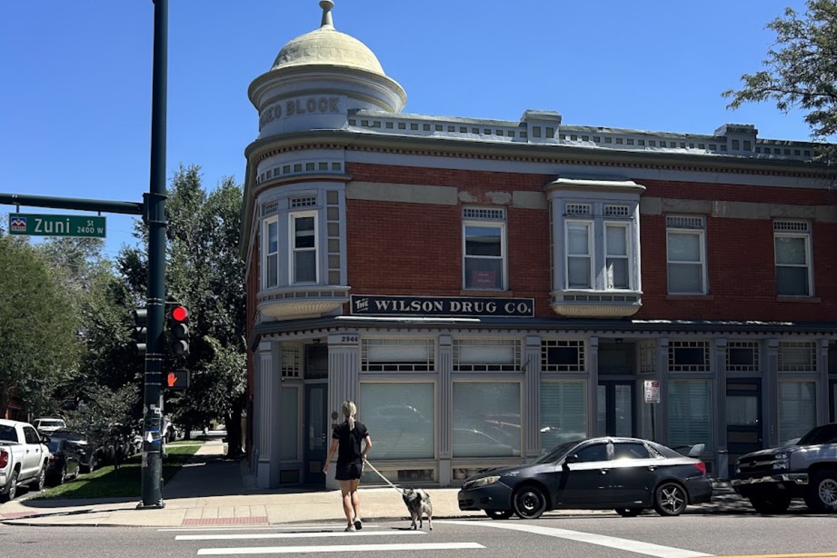 Historic red brick corner building with a domed turret and Wilson Drug Co. signage at Zuni Street in LoHi, Denver