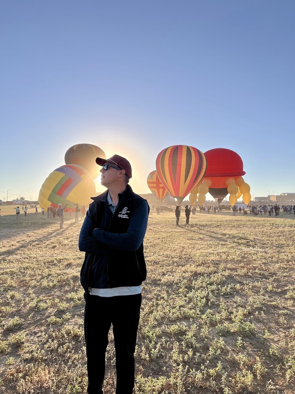 Jackson in a cap and sunglasses at sunrise in a field of hot air balloons