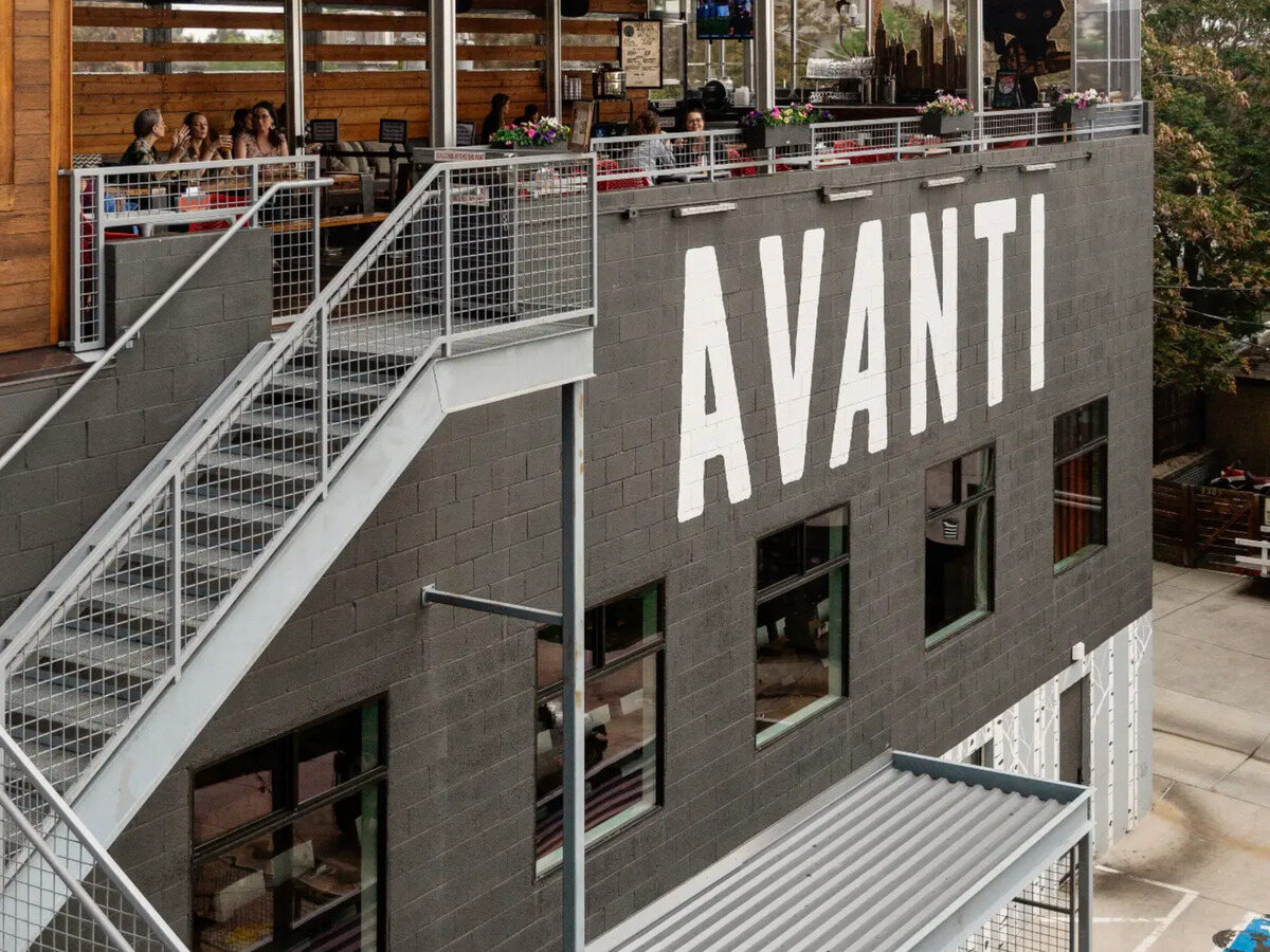 Avanti food hall with a rooftop patio and painted signage on a gray block building in Denver