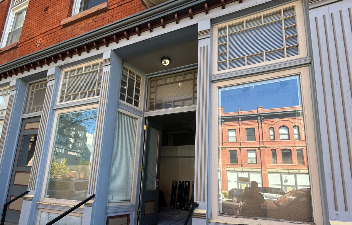 Close view of the historic Zuni Street storefront cornice, fluted pilasters, and transom windows during renovation