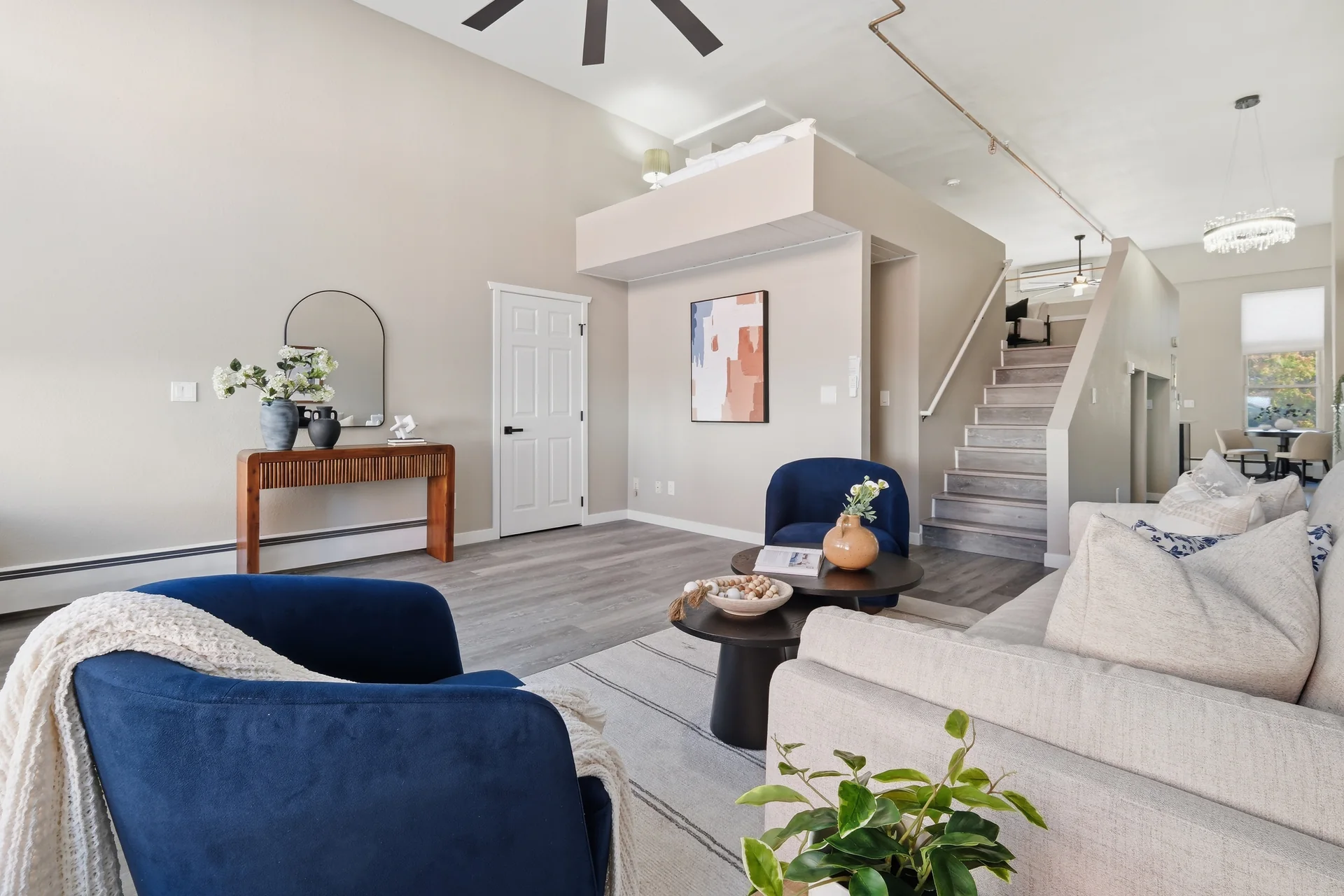 Zuni Loft living room with navy chairs, cream sofa, console table and stairs to the open loft bedroom